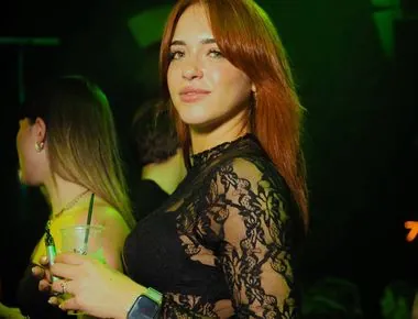 Ragazza dai capelli rossi con un drink sotto le luci verdi