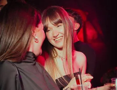 Due amiche ridono insieme sotto le luci rosse