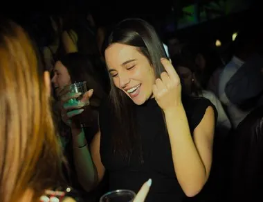 Ragazza sorride e balla con un drink