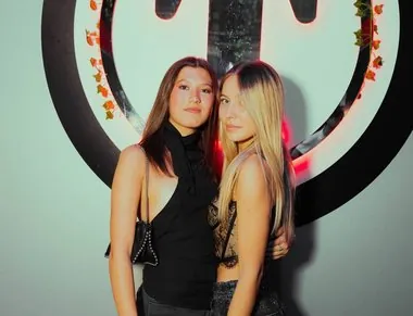 Due amiche davanti al grande logo illuminato