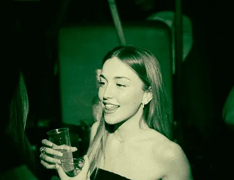 Ragazza sorridente con un drink sotto la luce verde