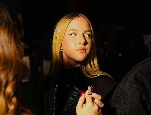 Ragazza bionda vestita di nero sotto luci calde