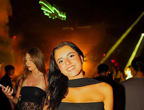 Due amiche tra fumo e fasci di luce arancioni
